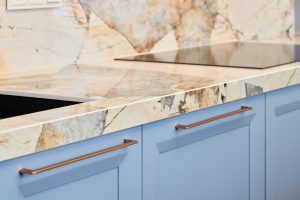 This stylish kitchen showcases a luxurious marble countertop paired with contemporary cabinetry in a chic blue design